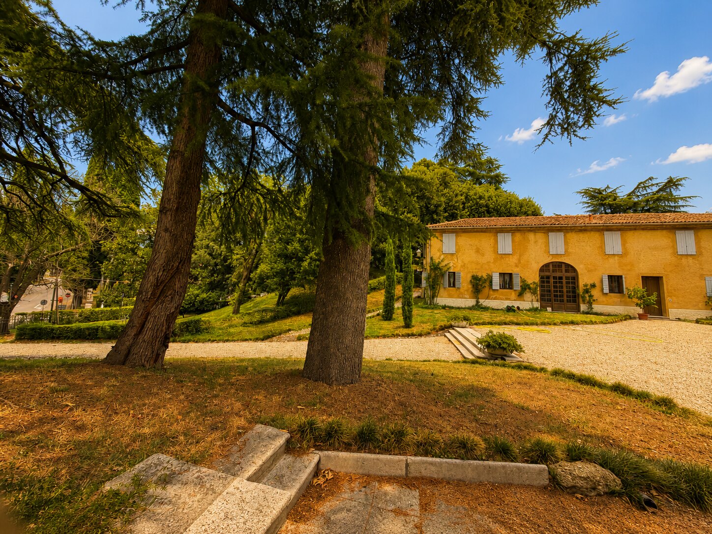 Facciata di Villa Giolai dal parco, incorniciata da alberi secolari
